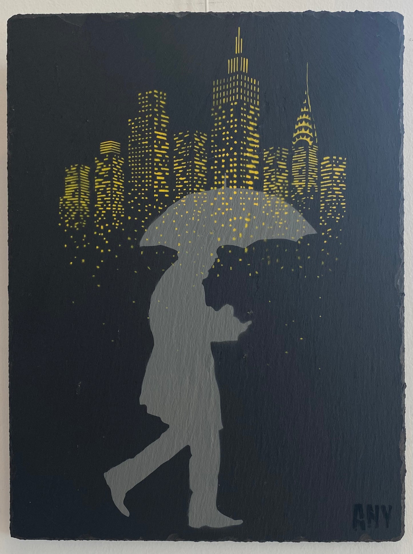 Dream Drops Slate Edition di Any. Opera unica spray e stencil su ardesia rappresentante un uomo che cammina sotto la pioggia con la città di New York sullo sfondo | CD Studio d'Arte